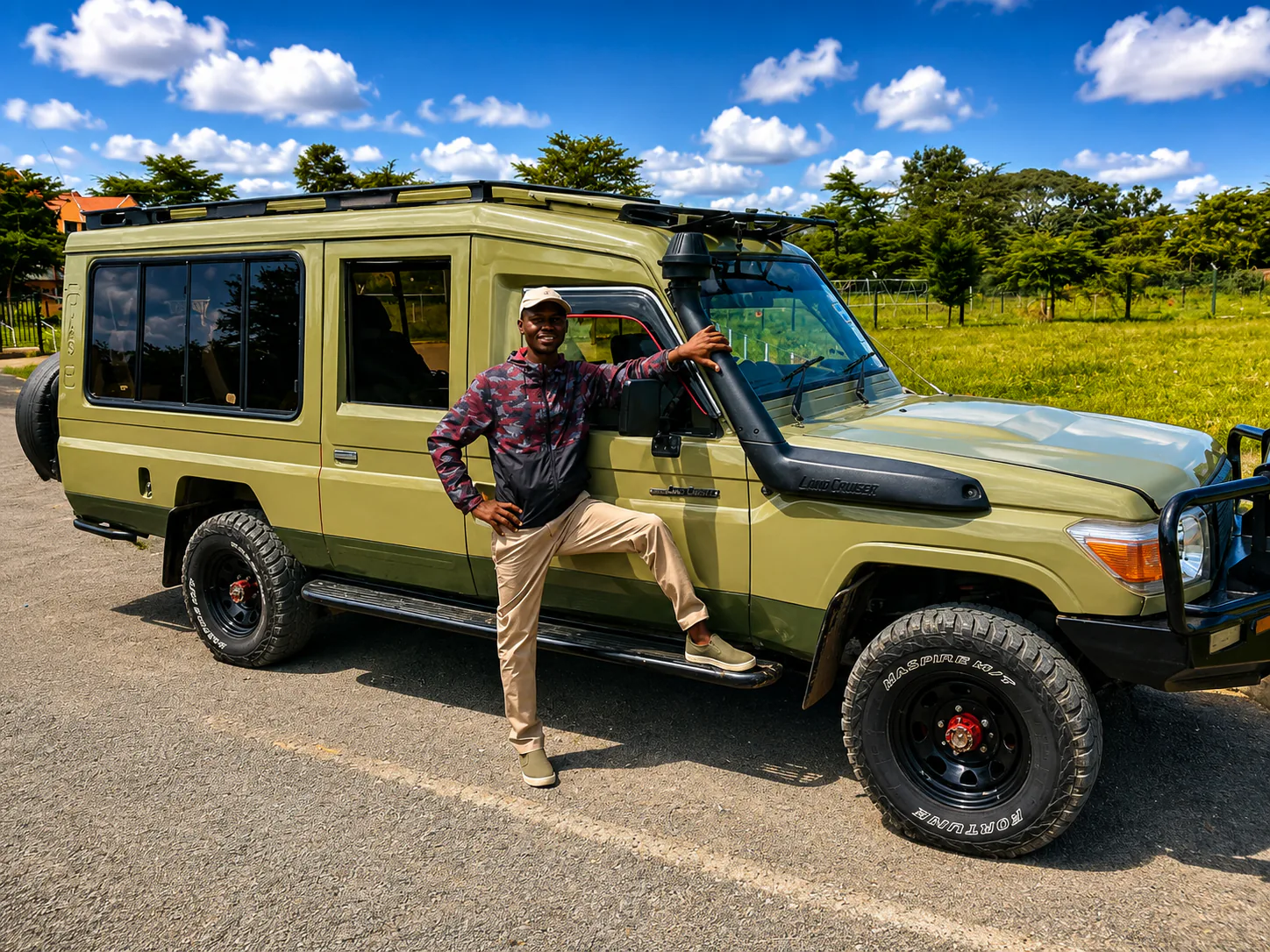 Safari guide standing beside a green four-wheel-drive vehicle